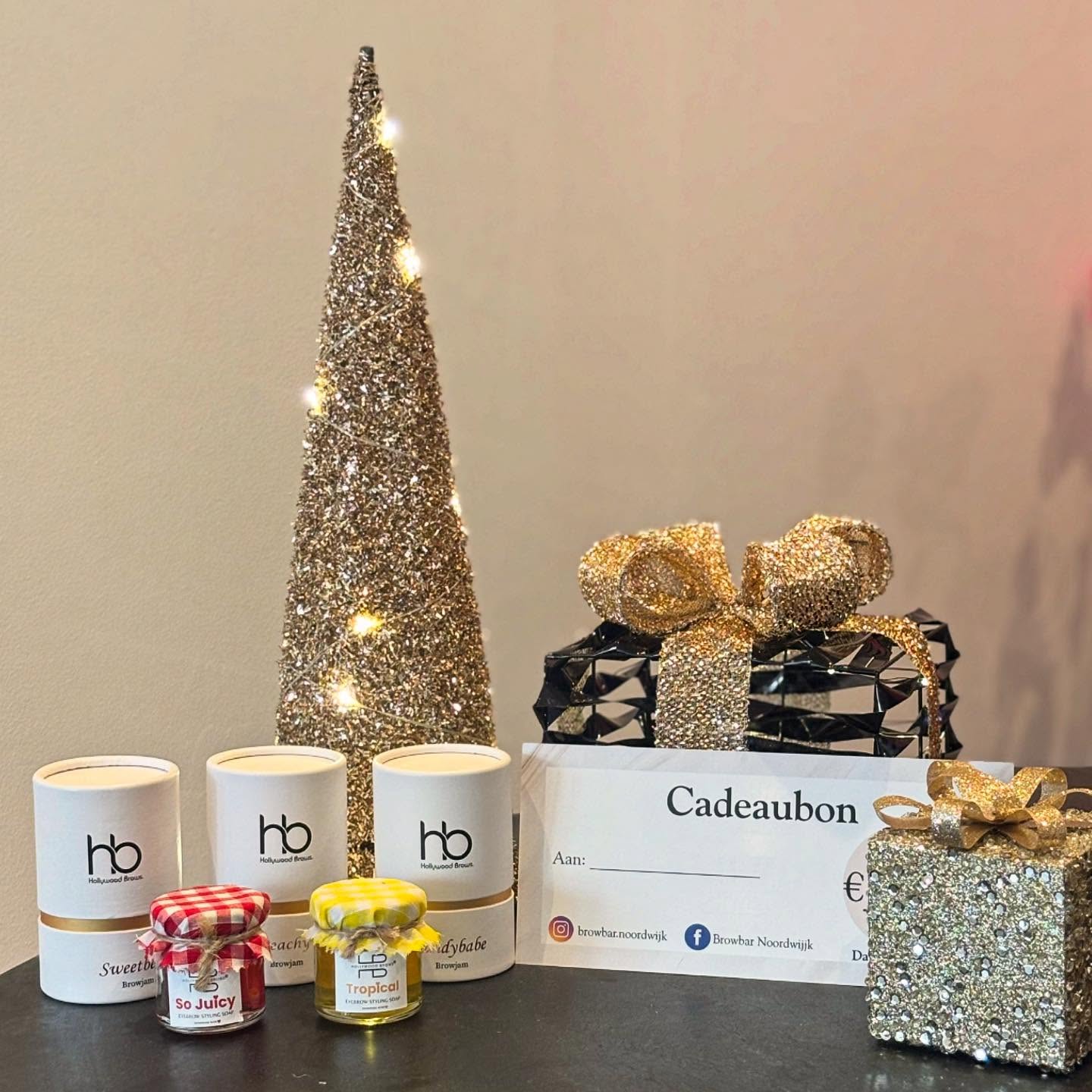 Cadeaubon van Browbar Noordwijk naast potjes browjam, ingepakte cadeautjes en een glinsterende kerstboom